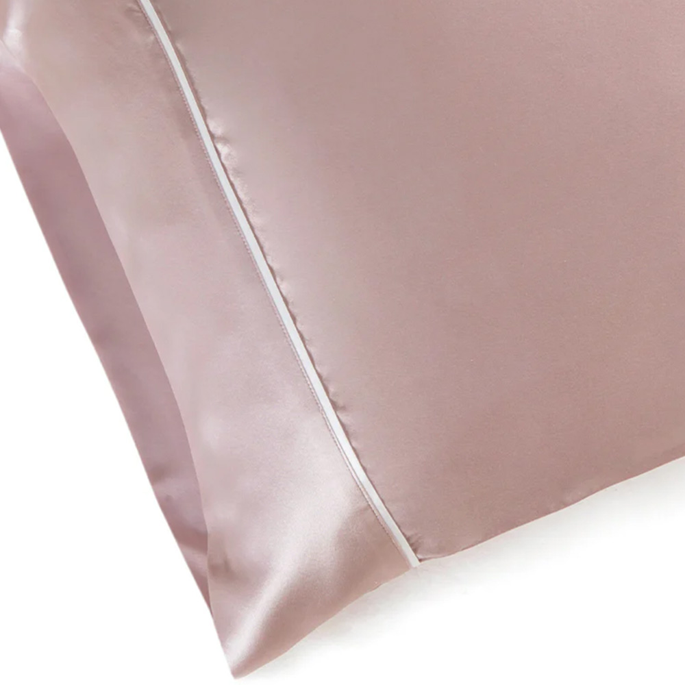 Detail shot of white piping edge on pink silk pillowcase